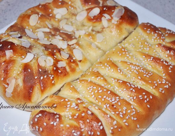 Тесто раскатать в виде круга, выложить начинку по центру. Края порезать по диагонали и свернуть внахлест.  Залепить уголки, смазать желтком, смешанным с сахаром. Посыпать кунжутом. Выпекать при 180 гр. около 30 минут.