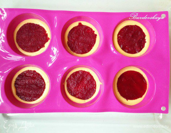 Заполнить на половину сферические силиконовые формочки. Сверху  выложить кружок из конфитюра (такого же размера как и кружок фундучного дакуаза). Убрать в морозильную камеру.