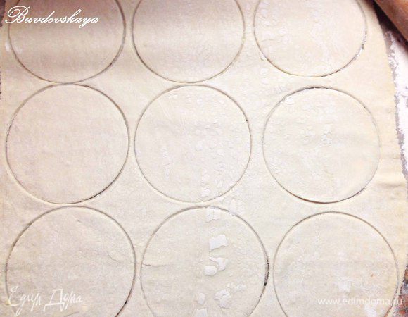 На присыпанной рабочей поверхности раскатать тонко тесто и вырезать из него кружки диаметром 11-12 см.