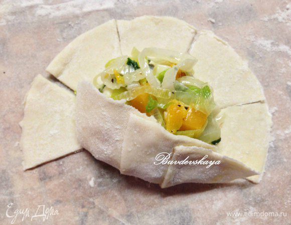 Выложить начинку (примерно 1,5 ст.л.) на середину теста и начинать загибать лепестки, предварительно смоченные водой, чтобы лучше держались. Слегка прижать лепестки друг к другу.