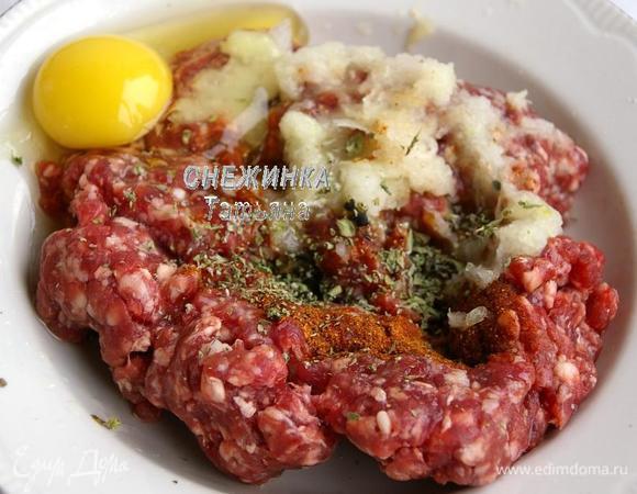 В фарш добавляем соль, смесь перцев, майоран, ягоды можжевельника, яйцо. Луковицу чистим и натираем на мелкой тёрке в фарш. Хорошенько всё перемешиваем.

