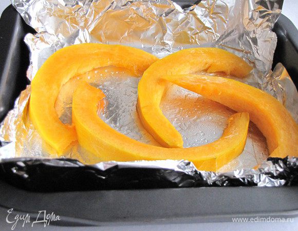 Тыкву нарезать ломтиками, смазать растительным маслом, выложить на противень, застеленный фольгой и запечь в духовке около 30 минут при 180 град.