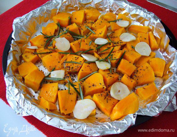 Разогреваем духовку до 180-200°C. Тыкву очищаем, режем небольшими кусочками. Противень или форму для выпекания выстилаем фольгой. Щедро поливаем кусочки тыквы оливковым маслом, посыпаем солью и перцем. Чеснок нарезаем сверху пластинками, иголки розмарина раскидываем по всей поверхности тыквы. Выпекаем минут 15-20 до готовности тыквы.