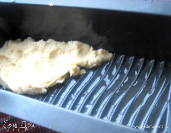 Для пластовой ватрушки возьмём силиконовую форму "кирпичик", смажем растительным маслом и распределим слой теста по дну толщиной с палец.