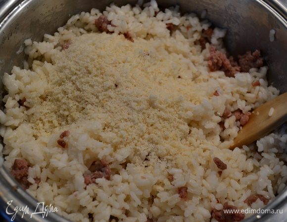 Через 10 минут открыть рис, перемешать ложкой и выложить к рису обжаренный фарш. Добавить тертый сыр. И снова перемешать. Проверить на соль и перец.