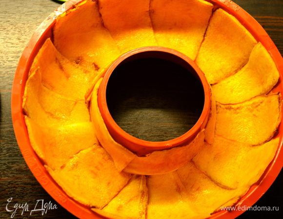 Духовку разогреть до 180 С. Форму для выпечки кексов с дыркой посередине смазать немного маслом. Выложить по всему периметру дольками тыквы. 
