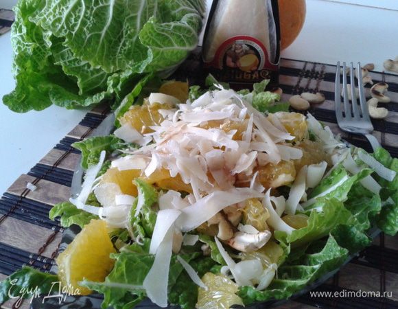 Выложить на тарелку листья капусты и апельсин, полить заправкой. Затем посыпать орешками, и хлопьями потереть сыр Джюгас 12 месяцев выдержки.
