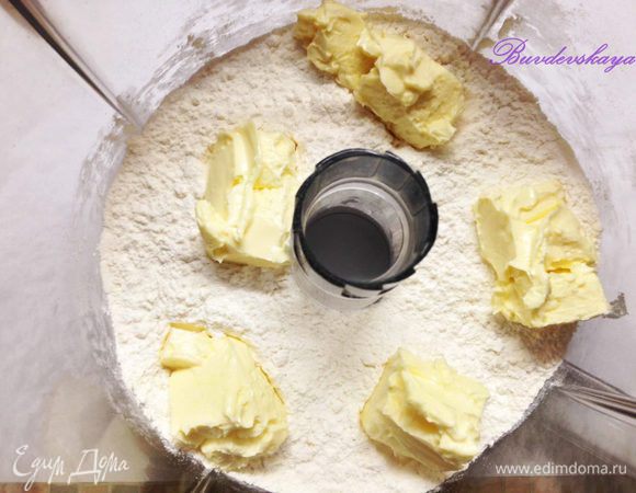 Вынуть сливочное масло из холодильника и дать постоять минут 20 при комнатной  температуре. Нарезать крупными кубиками. В чашу комбайна положить муку, добавить масло и порубить до состояния крошки.
