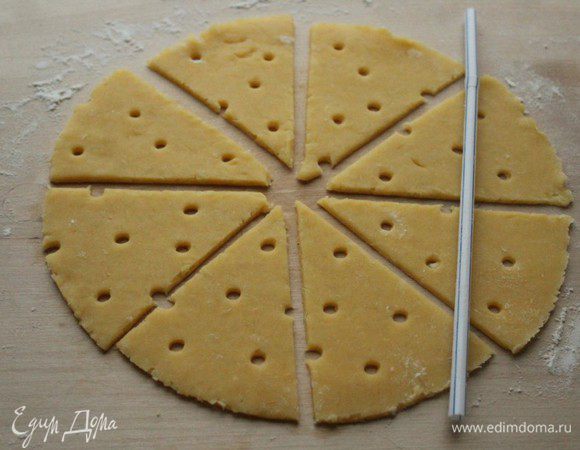 Тесто разделить на две части. Раскатать круглый корж, разрезать на треугольники и при помощи коктейльной трубочки сделать отверстия. (так называемые сырные дырки)))