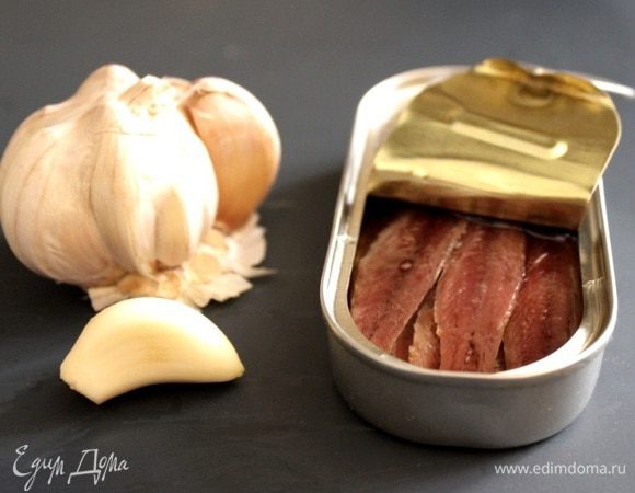 Чеснок раздавить прессом, а затем растереть вилкой в пюре вместе с анчоусами.