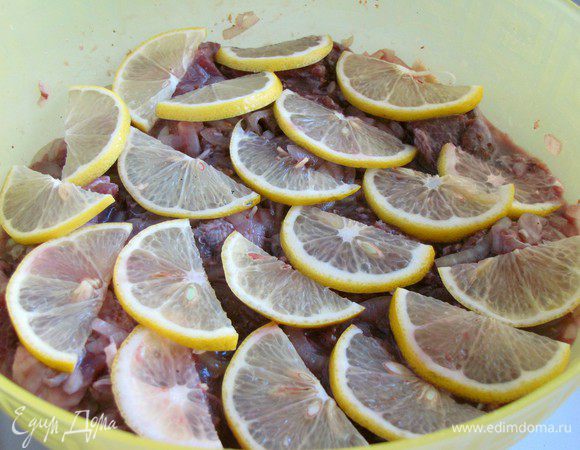 Влить вино, добавить лимон, нарезанный тонкими ломтиками. Все еще раз хорошо перемешать. Прижать мясо тарелкой, чтобы маринад покрыл полностью все мясо и оставить мариноваться на 1 час.