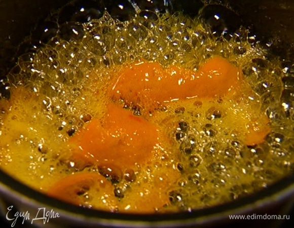 С оставшегося апельсина овощечисткой срезать длинную спираль из цедры, выложить ее в кастрюлю с карамелью, поместить на огонь и варить несколько минут.