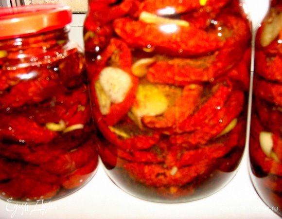 Подготовить стерилизованные банки и крышки. Чеснок очистить и порезать дольками поперек. Готовые помидоры вынуть из духовки, закладывать в банки слоями, каждый слой пересыпать чесноком. Я, кладу дольку чеснока на каждую помидорку. Залить все оливковым маслом и закатать. Хранить в прохладном месте, но лучше не в холодильнике,т.к. оливковое масло замерзает.