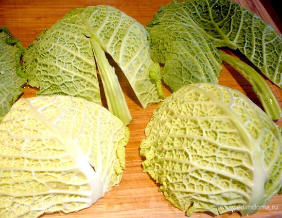 Для начала поставим в морозильную камеру емкость с холодной водой, минут примерно на 20, после этого приготовим листья савойской капусты, помоем их и вырежем грубые жилки в середине листа или, если листья достаточно небольшие, можно просто немного подрезать жилку с изнаночной стороны, там где она наиболее сильно выступает. Теперь отвариваем листья в подсоленной кипящей воде под гнетом в течение 3 минут. Сливаем воду и сразу же окатываем листья ледяной водой из морозилки. Затем выкладываем их между двумя полотенцами и аккуратно промокаем с обеих сторон.