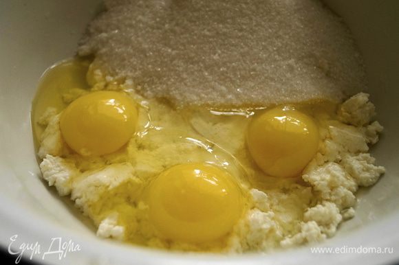 Творог растереть, добавить сахар и яйца. Все хорошо перемешать до однородной массы, так чтобы сахар растворился.