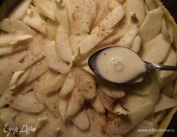 Верхний слой посыпаем корицей и ванилином, выкладываем между ломтиками груш кусочки сливочного масла и заливаем заливкой.