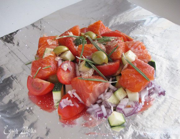 Выложить на овощи рыбу, посыпать листиками розмарина и чесноком, посолить, поперчить.