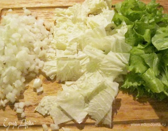 Дюжину листьев китайской капусты разрезал пополам, вырезав кочерыжку.  Кочерыжки нарезал мелким кубиком, а листья порезал квадратиком. Также нарезал листья кучерявого салата. 