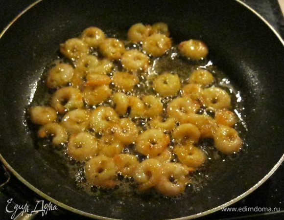 Креветки остудил и очистил, только несколько оставил целыми для украшения. Поставил разогреваться сковородку с четырьмя ложками растительного масла. Пол чайной ложки меда растворил в четырех ложках рассола оставшегося от креветок. Очищенные креветки положил в горячую сковородку и, во время жарки, поливал их медовым раствором. Это нужно что бы креветки карамелизовались и приобрели аппетитный вид.