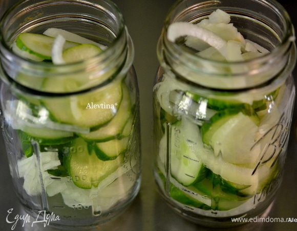 Огурцы и лук тонко порезанные положить в банки поделив ровно.