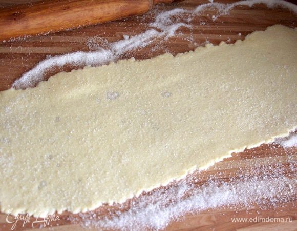 Делим тесто на 2 части. Раскатываем на присыпанной сахаром поверхности в тонкий прямоугольный пласт. Сверху также присыпаем тесто сахаром.
