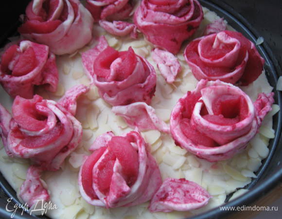 Тесто раскатать и из части его вырезать круг диаметра формы, из другой части  нарезать длинные полоски шириной 2 см, смазать кисточкой с двух сторон небольшим количеством свекольного сока, положить яблочные ломтики на полоски теста вдоль, скрутить розочки. Основу теста положить в смазанную маслом форму. Яйцо взбить венчиком, слегка смазать тесто. Посыпать миндальными лепестками. Сверху выложить розочки, кисточкой смазать яйцом розочки.
 		 
