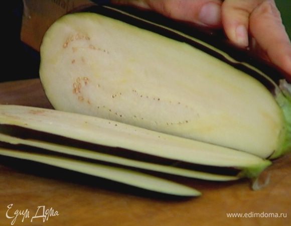 Баклажан нарезать вдоль тонкими пластинками и смазать их с обеих сторон оливковым маслом.