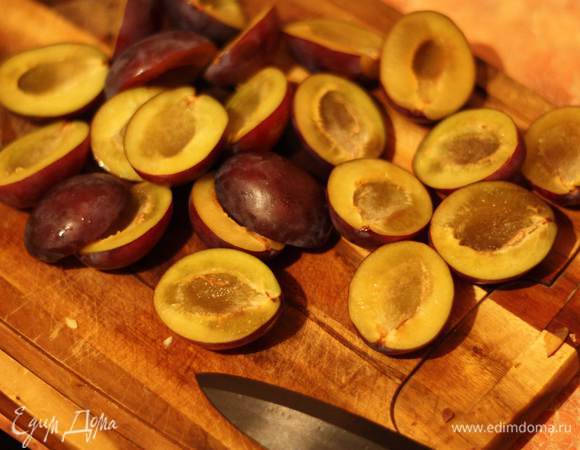 Тем временем сливы разрезаем пополам и убираем косточку.