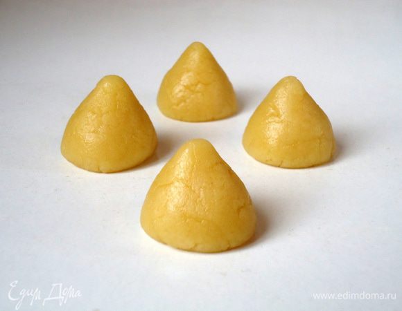 Сформовать печенья конусообразной формы.  Если печенье с начинкой, то кусочки теста лучше сделать по 20-21 гр. На каждый кусочек теста положить по две четверти окошечка шоколада и защипнуть, так же придав форму конуса.

