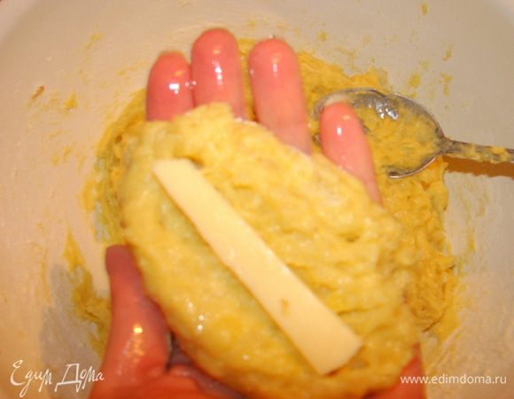 Смазать руки растительным маслом, чтобы тесто не прилипало. Столовой ложкой отщипнуть кусочек теста. Внутрь погрузить брусочек сыра. 