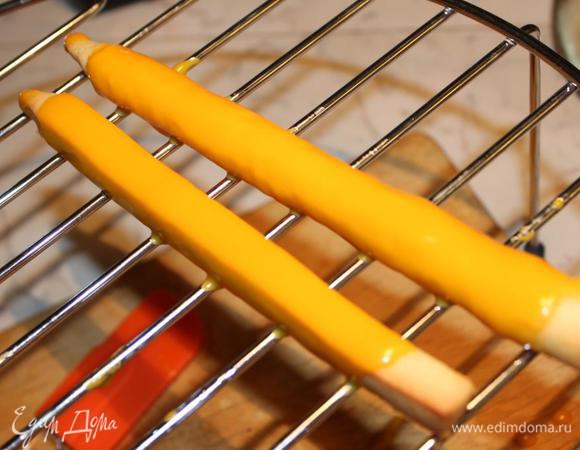 Каждую заготовку для карандашей обмазать глазурью (держать за кончик и с помощью ложки наливать на карандаш глазурь). Лучше разместить их на решетку, чтобы лишняя глазурь могла свободно стекать.