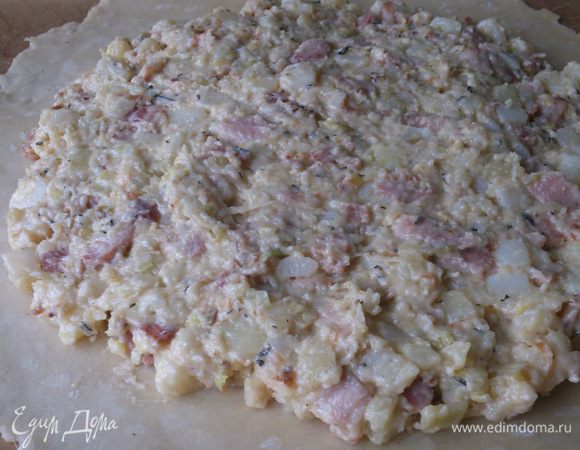 Тесто раскатать тонким пластом круглой формы и перенести на лист. Выложить на него начинку по центру, оставив край свободным на 2–3 см.