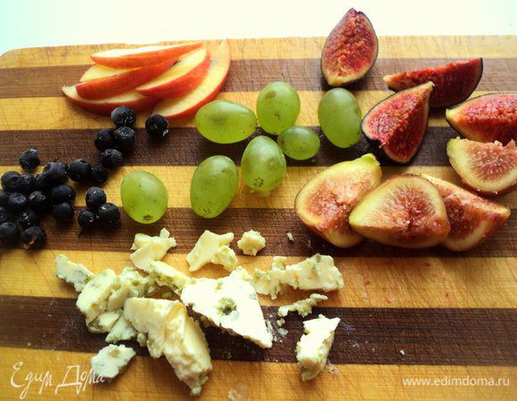 Инжир разрезать на 4 части, яблоко порезать тонкими дольками. Виноград оборвать с веточки и помыть. Чернику помыть и просушить на бумажной салфетке. Сыр порезать небольшими кусочками, орехи очистить от скорлупы и порезать крупными кусочками.