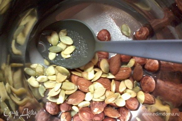Подсушить орехи на сковородке (тыквенные семечки не подсушивать, иначе потом они сгорят в карамели), смешать воду, сахар и орехи с семечками.