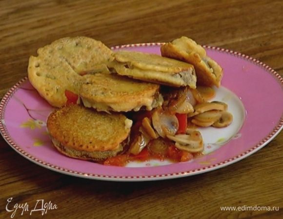 Подавать зеленые помидоры в кляре с обжаренными грибами с помидором, луком и чесноком.