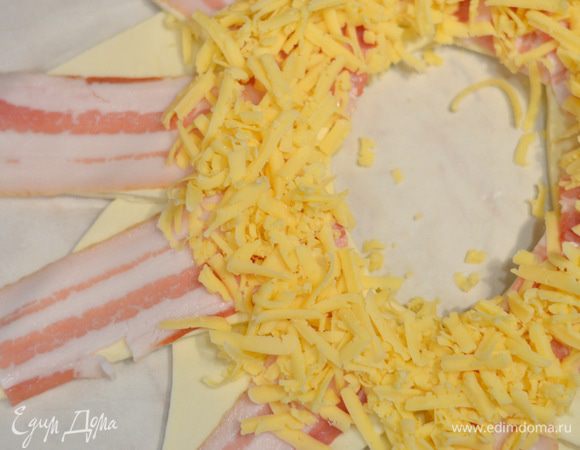 Натереть сыр на терке и выложить половину по кругу.