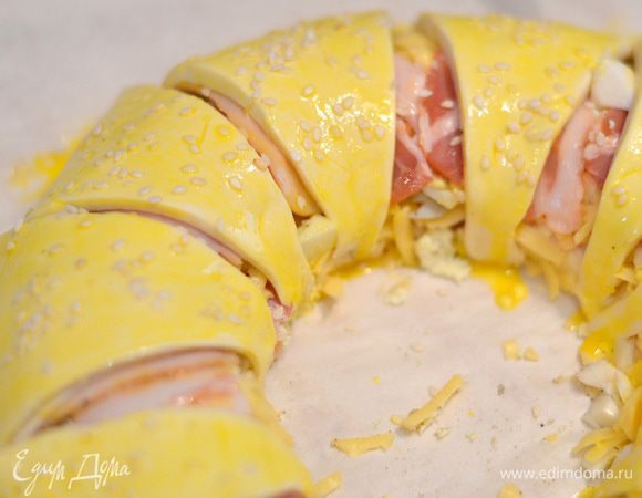 Смазать пирог взбитым желтком, добавив немного молока, посыпать кунжутом и выпекать в предварительно разогретой духовке при температуре 180–190°C около 25–30 минут до золотистой корочки.