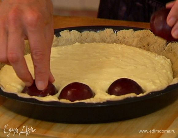 Вынуть пропеченный корж из духовки, вылить на него творожный крем, на крем выложить половинки слив, срезами вниз и слегка притопить их.