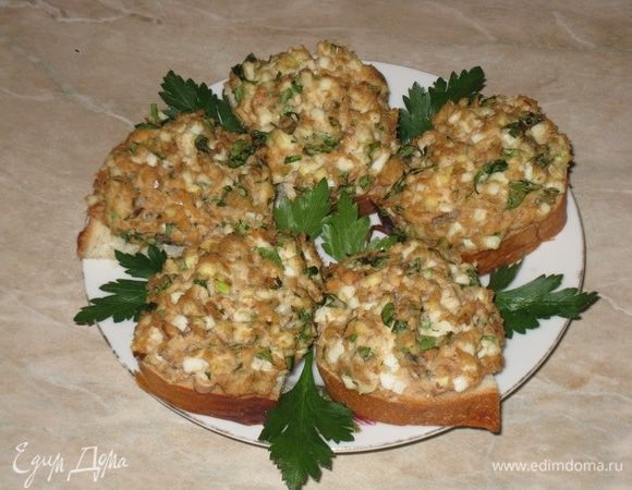 На готовые гренки выкладываю смесь рыбы с чесноком и луком. Украшаю при подаче зеленью. Можно украсить бутерброды кольцами лука шалот.