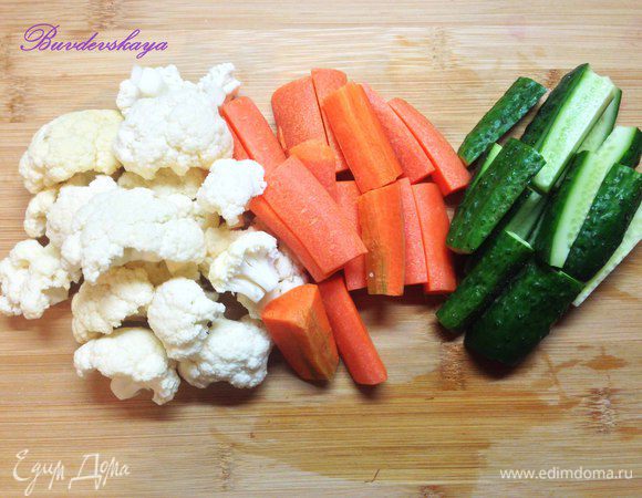 Все овощи вымыть и обсушить. Капусту разобрать на небольшие соцветия. Морковь очистить и нарезать крупными брусочками. Огурцы нарезать также брусочками. Лук и чеснок очистить. Если у Вас крупный шалот, то его можно разрезать на 2 (4 части). В одну миску сложить огурцы. В другую – цветную капусту и морковь. Овощи присыпать солью и оставить на 1 час. Слить выделившийся сок.