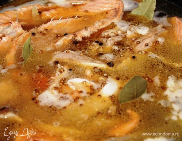 Пассерованные овощи выложить в большую кастрюлю, поверх их поместить рыбу, залить кипятком, добавить нарезанный на кубики картофель, лавровый лист, зерна кориандра, перец горошком и соль.