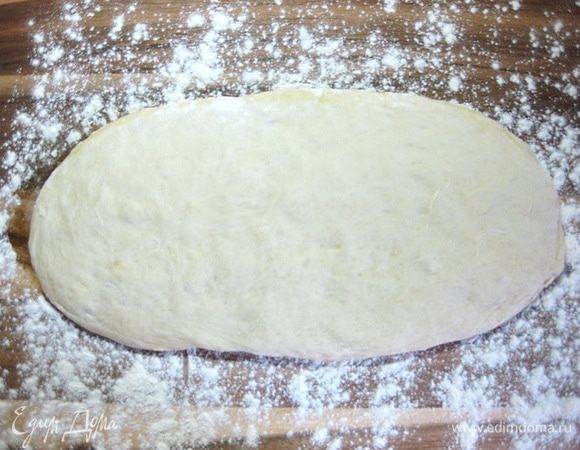 Подошедшее тесто выложить на присыпанную мукой рабочую поверхность и расправить руками в прямоугольник высотой около 3 см.
