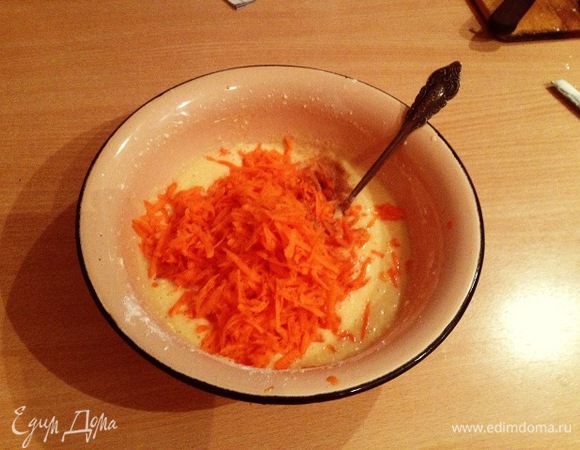 Сверху просеять муку с разрыхлителем, положить тертую морковь, щепотку корицы и хорошо перемешать.