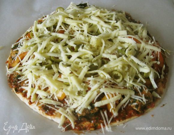 Далее оливки и мягкий сыр (в моем случае гауда), натертый на крупной терке.
Противень с пиццей поставил в горячую духовку на сорок минут.  Уже через пару минут кухня наполнилась ароматом чеснока из соуса. Даже котик прибежал, наверное, сыр учуял. Пармезан он не ест, зато гауду любит.