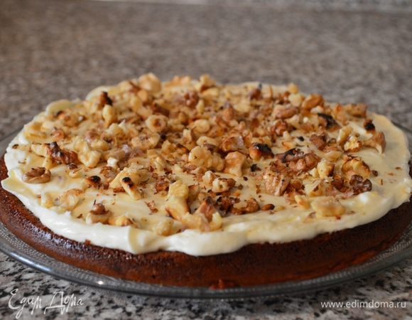 Крем присыпаем подсушенными грецкими орехами. Выкладываем верхнюю часть коржа и хорошенько промазываем оставшимся кремом.