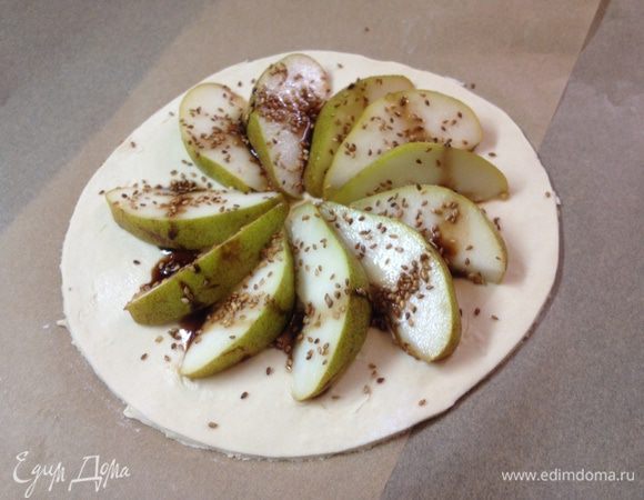 Выкладываем тесто на противень а сверху нарезанную на дольки грушу. 
Поливаем соусом и посыпаем кунжутом. 
