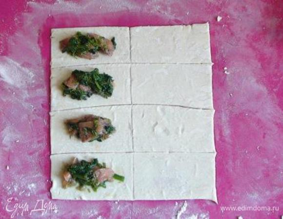 Раскатать тесто на присыпанной мукой столешнице. Разрезать его на одинаковые прямоугольнички (примерно 5х10 см). На половину прямоугольничков выложить начинку, сверху прикрыть оставшимися прямоугольничками.