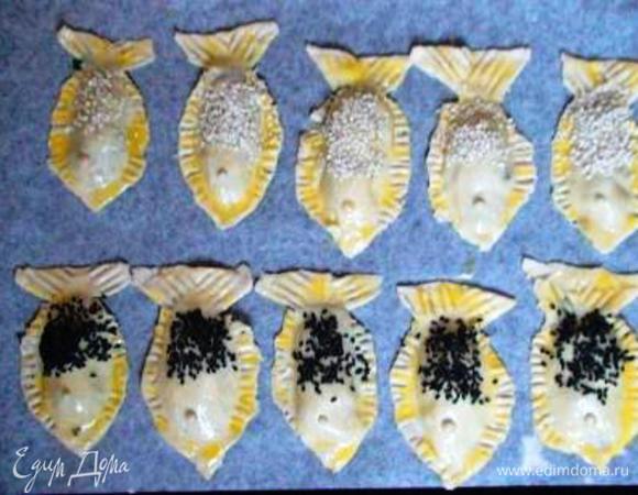 Противень выстелить пергаментом, выложить на него пирожки, смазать их взбитым желтком и присыпать кунжутом.