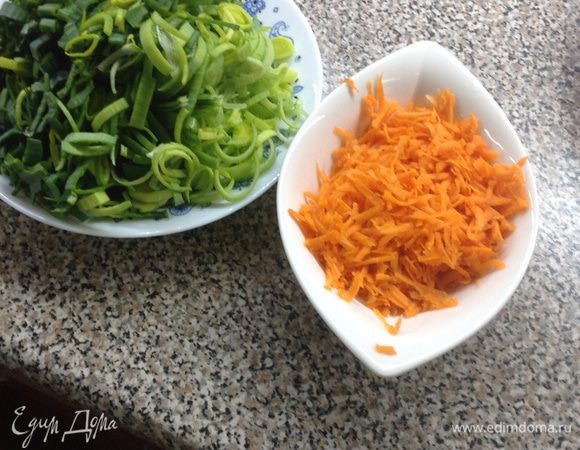 Натрите морковь. Нарежьте зеленую часть лука колечками (оставшуюся часть можно заморозить и использовать, например, в овощной лазанье).