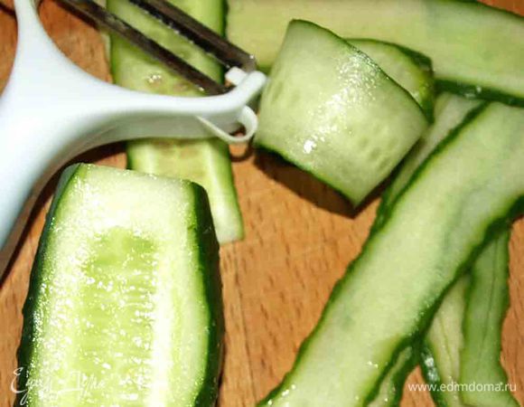 Огурец нарезать (овощерезкой) тонкими ломтиками.